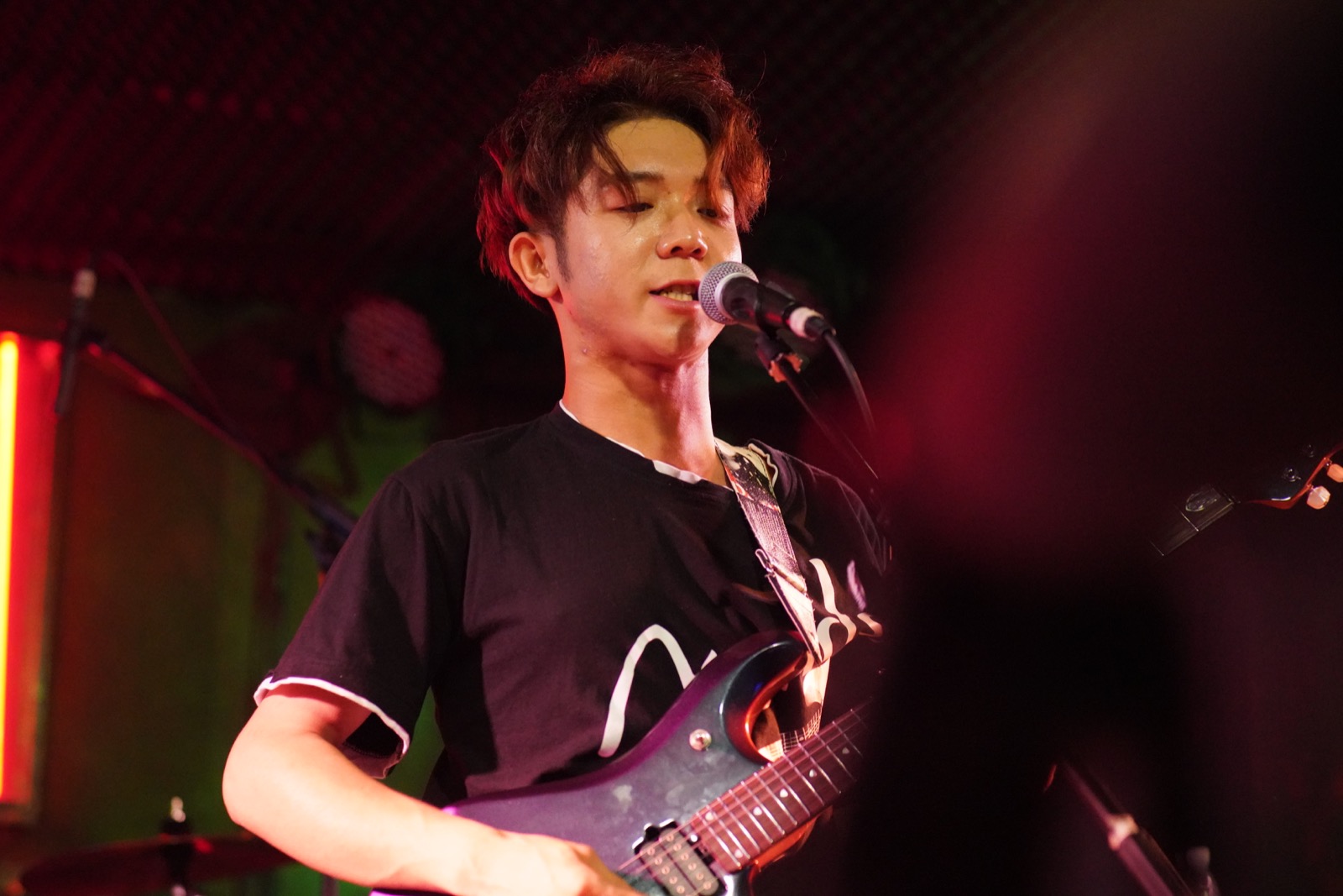Older singer playing guitar at microphone